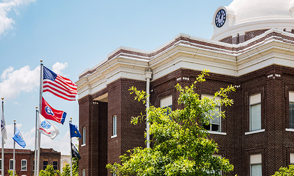 A large brick building with many flag poles in front.