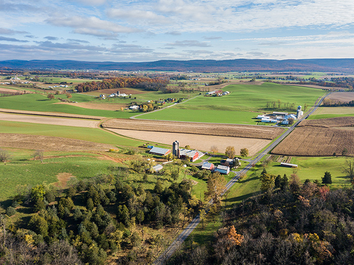 An aerial view of a rural farm community with forests and fields.